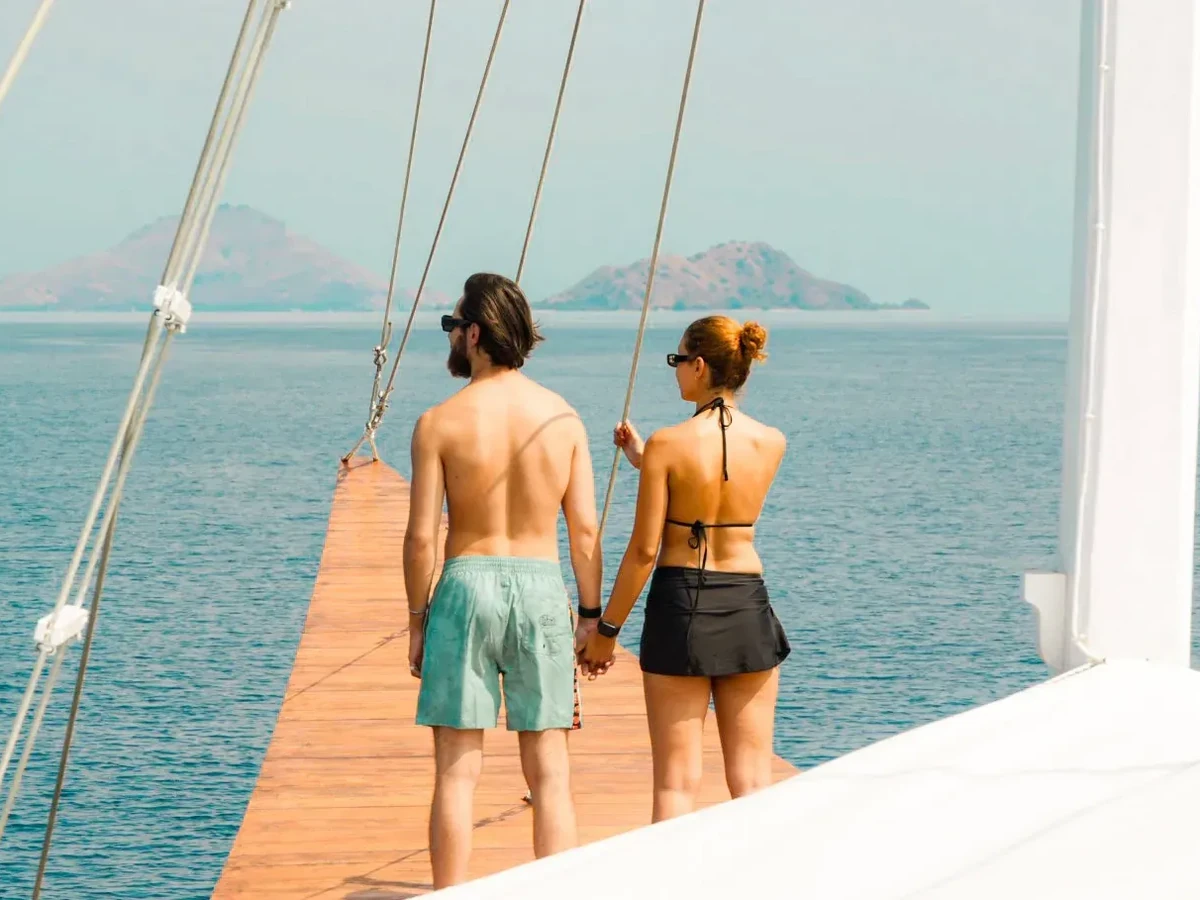A couple standing at the bow rail of a sailing boat as the light turns gold
