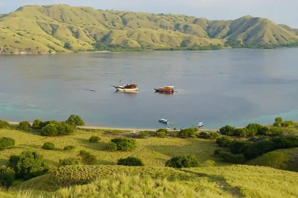 Green hills above a sheltered bay at Gili Lawa with boats at anchor