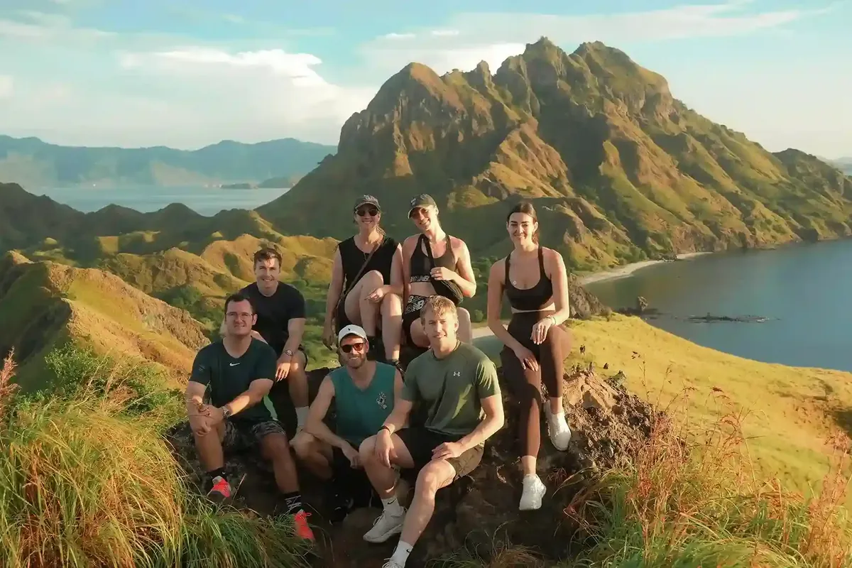 A group of travellers resting at the Padar Island viewpoint above the bays