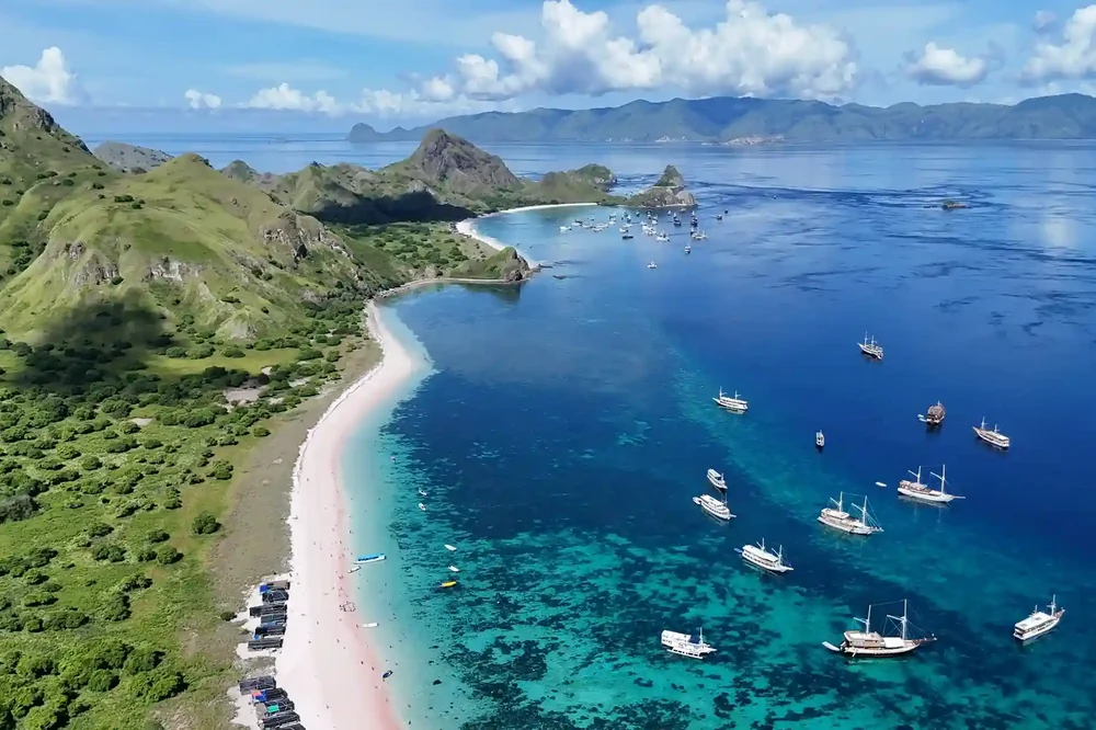 Aerial view of Pink Beach and turquoise shallows with boats moored offshore