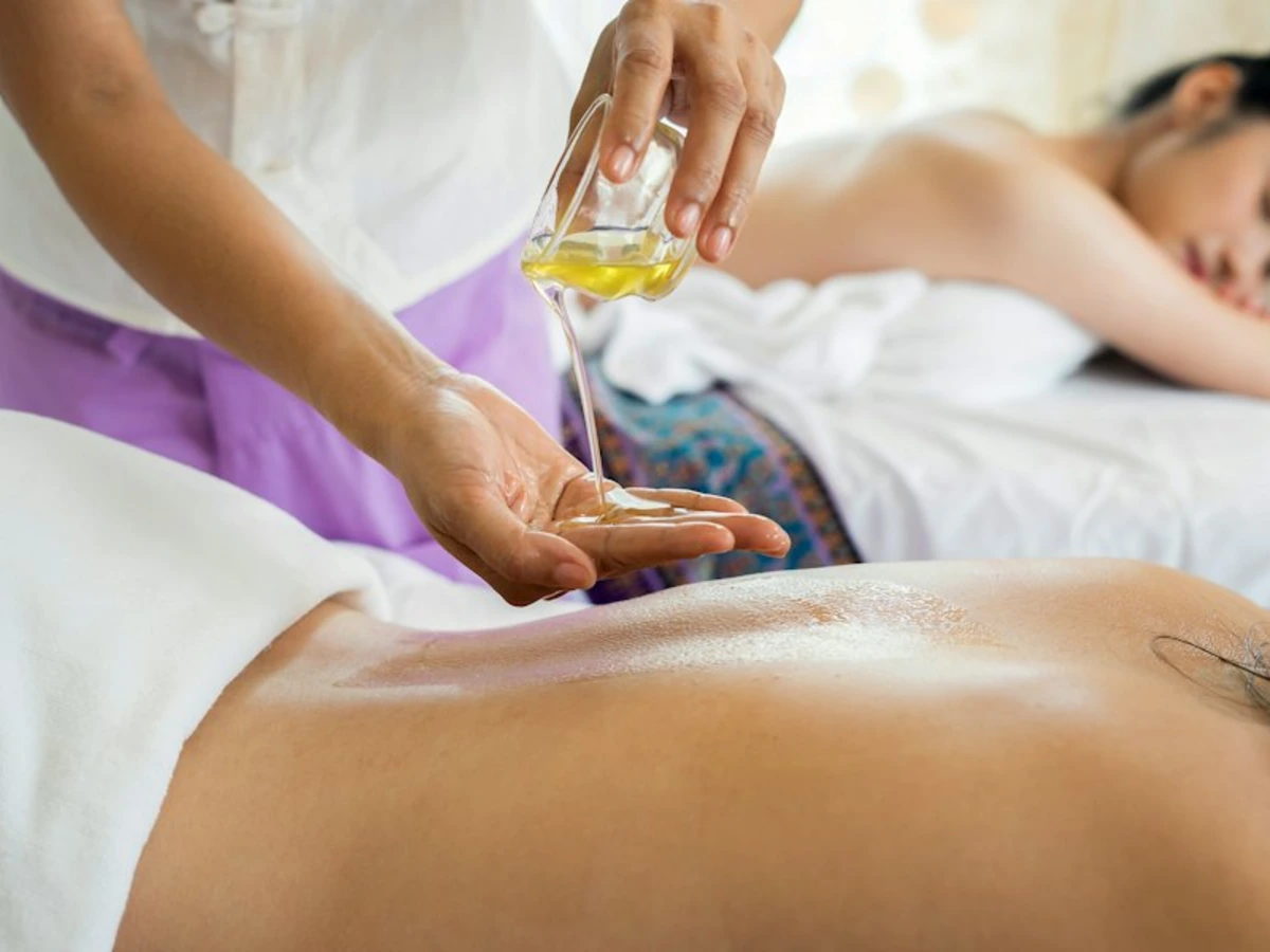 A therapist pouring warm oil during a traditional massage treatment